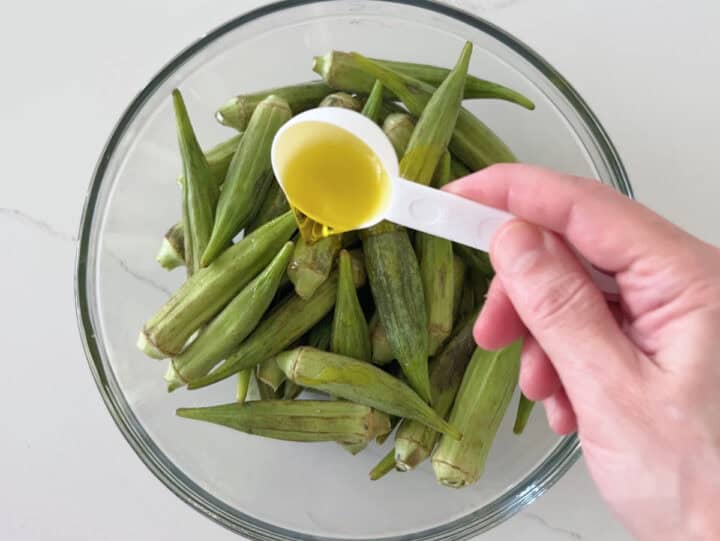 Adding olive oil to the okra.