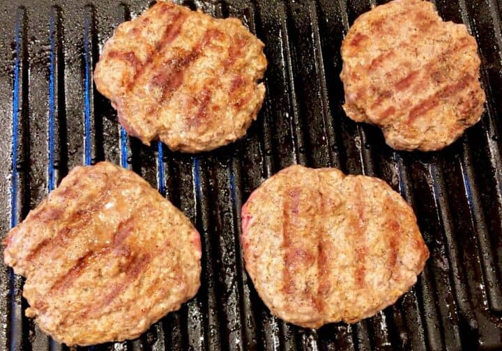 Four burgers on a grill.