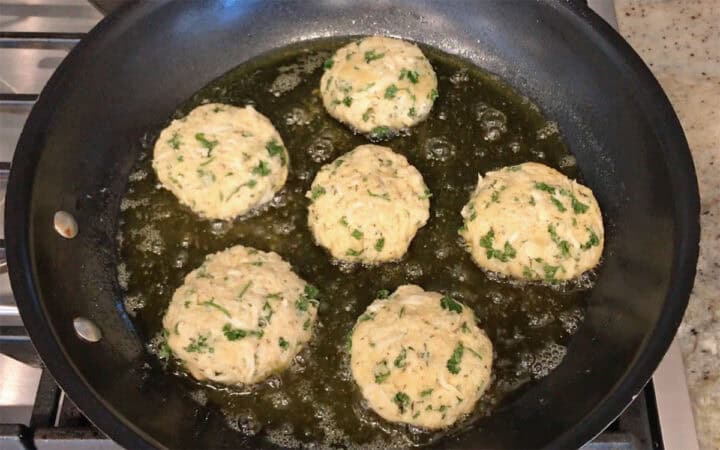 Six crab cakes in a skillet.