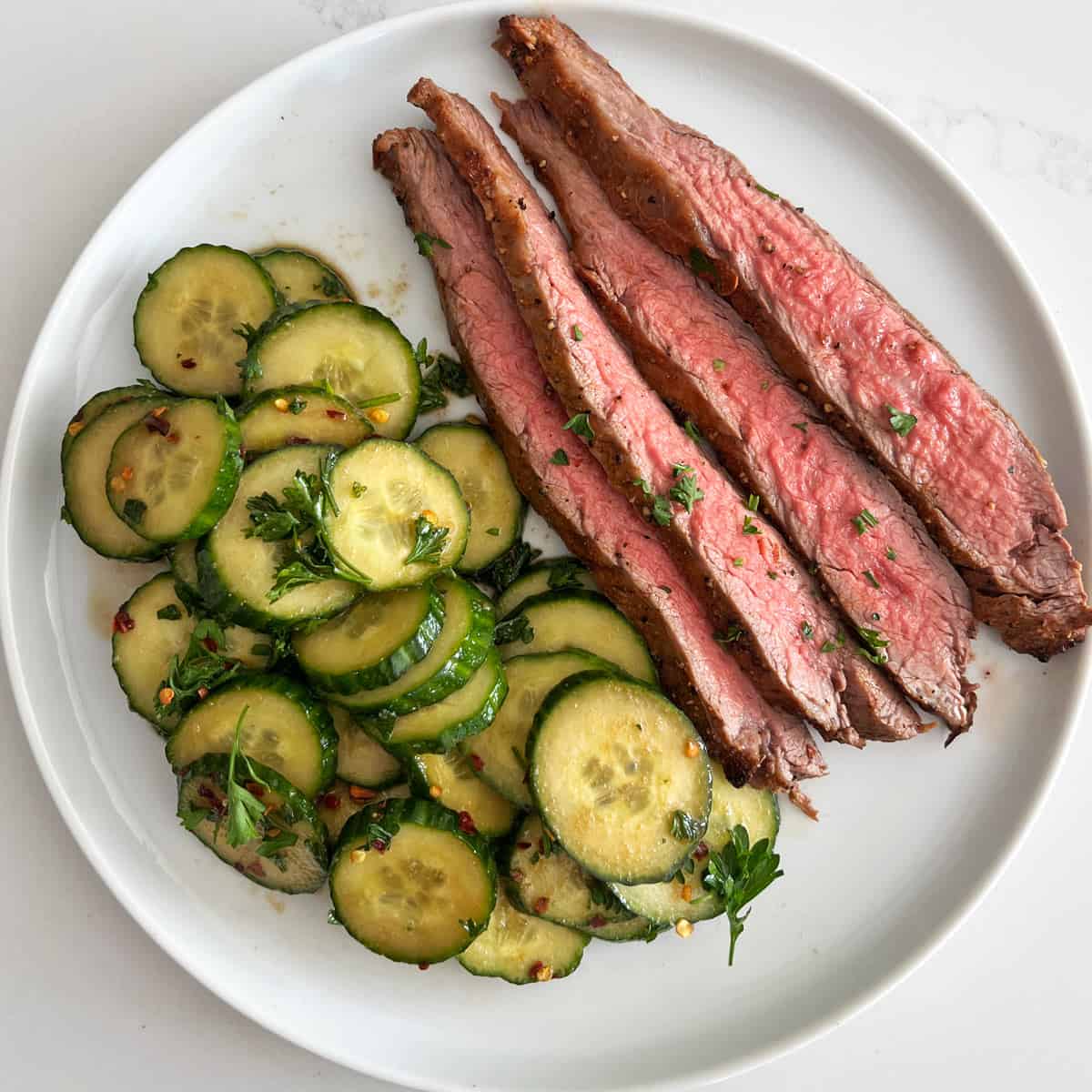 Flank steak is served with cucumber salad.
