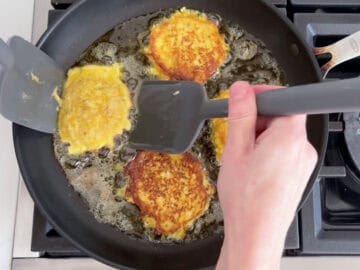 Flipping the fritters with two wide spatulas.