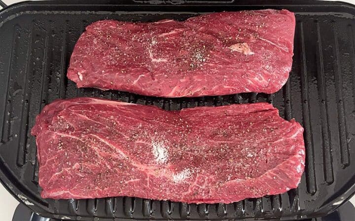 Two flat iron steaks on the grill.