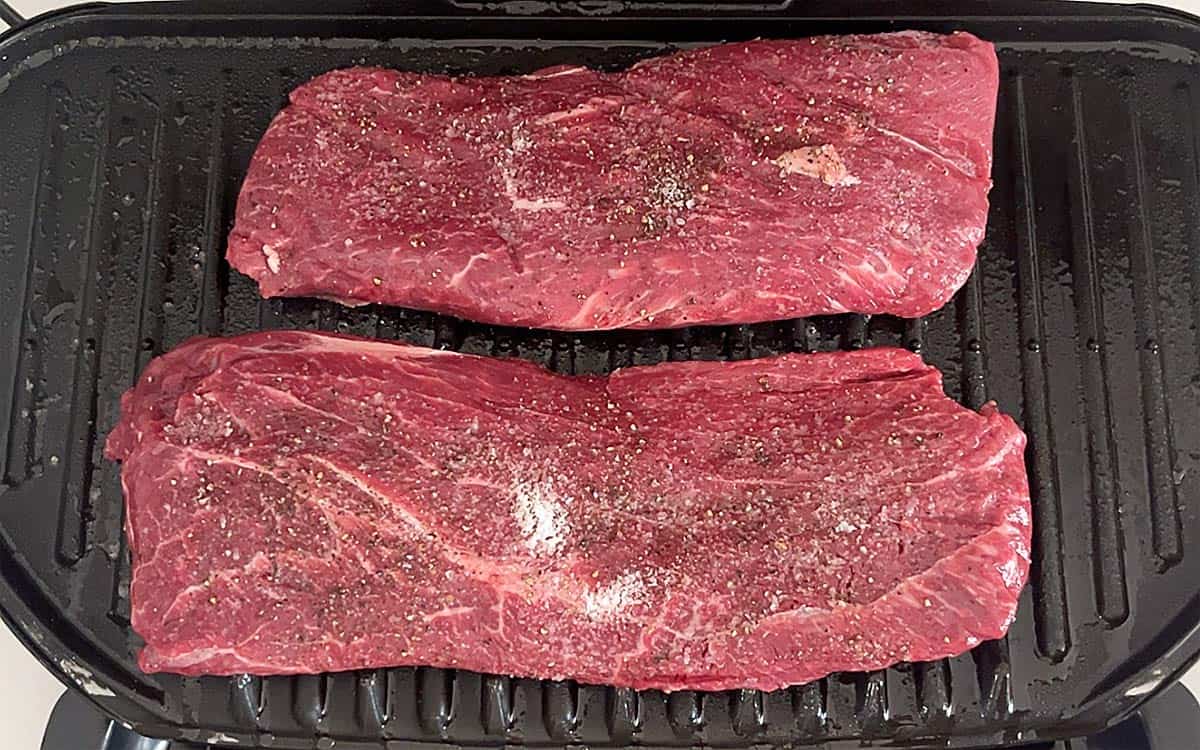 Two flat iron steaks on the grill.