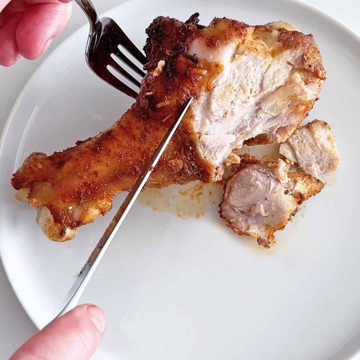 Cutting into a wing to show off its perfectly cooked inside.