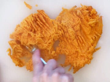 Mashing the sweet potato with a fork.