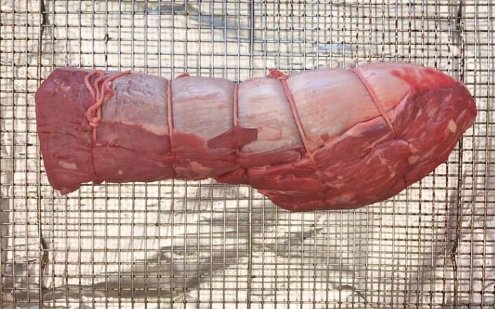 The raw roast is resting on the pan.