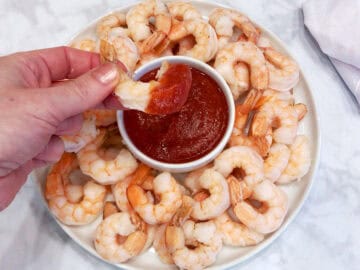 Dipping a shrimp into keto cocktail sauce.