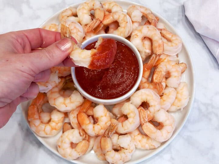 Dipping a shrimp into keto cocktail sauce.