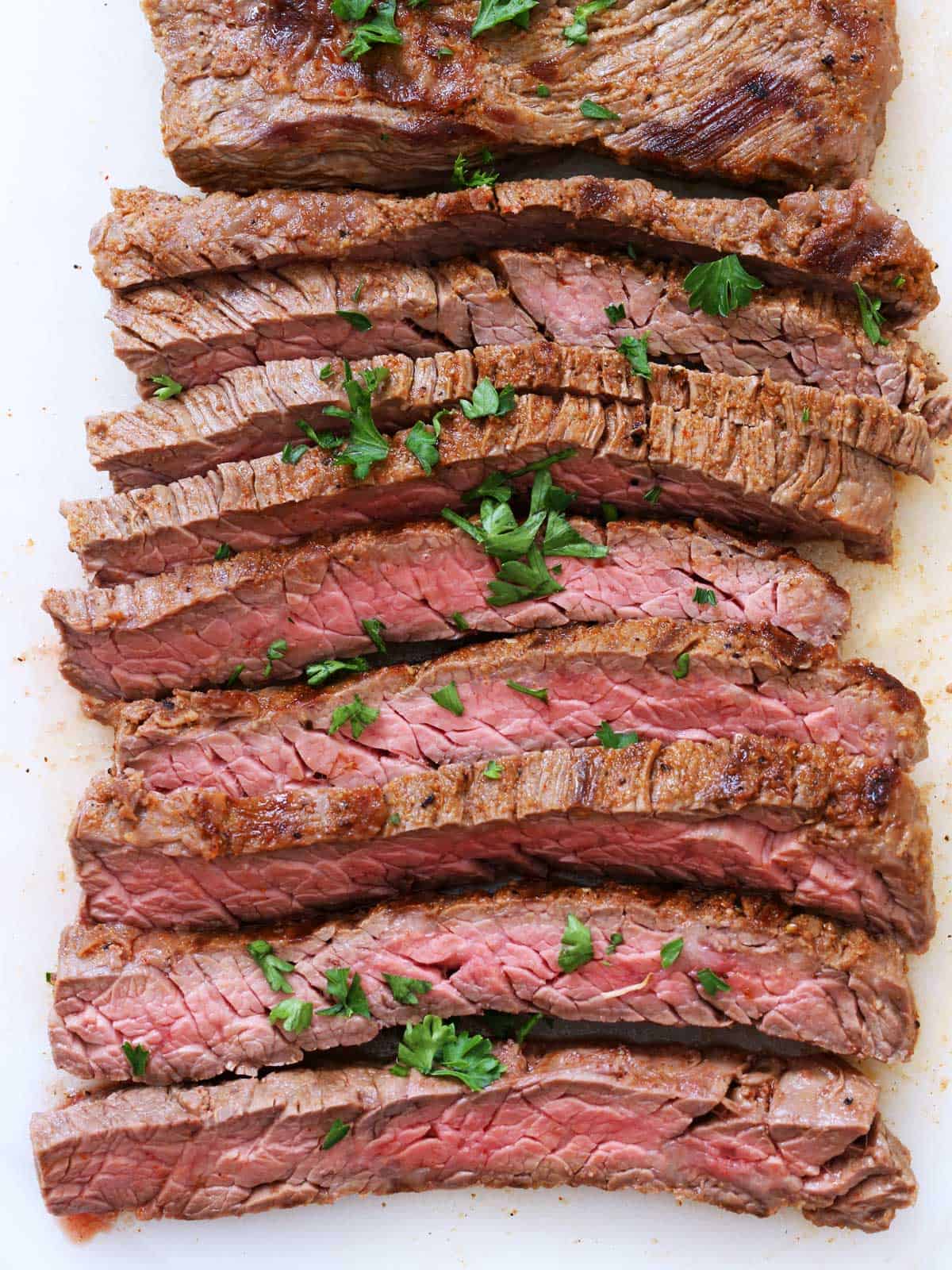 Skirt steak is served on a white cutting board.