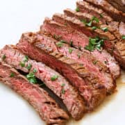 Skirt steak is served on a white cutting board.