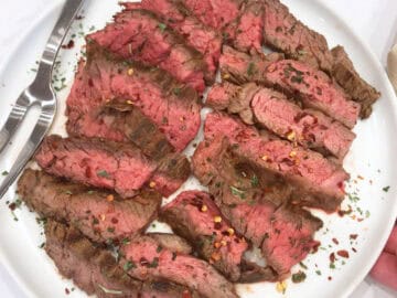 The sliced steak is served on a white plate.
