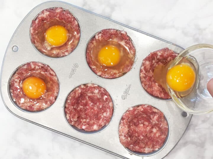 Adding the eggs to the muffin cups.