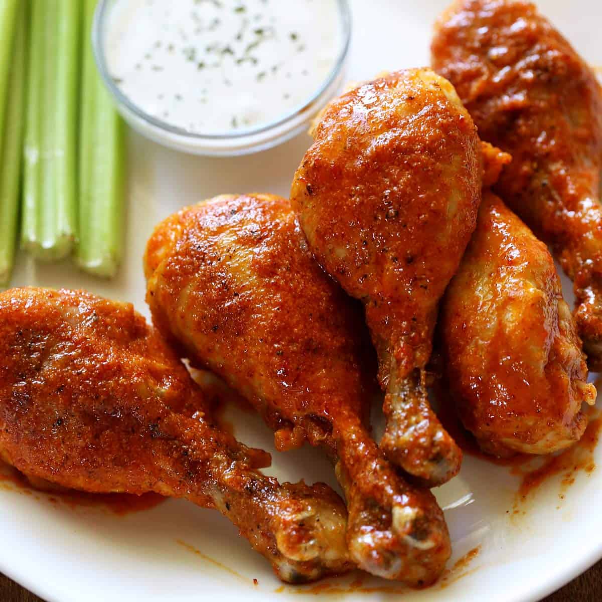 Buffalo drumsticks are served with celery sticks and ranch dressing.