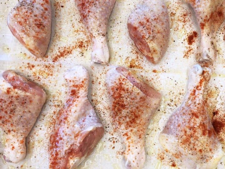 The raw drumsticks are arranged on the baking sheet.