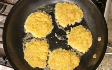 The fritters are cooking in a skillet.