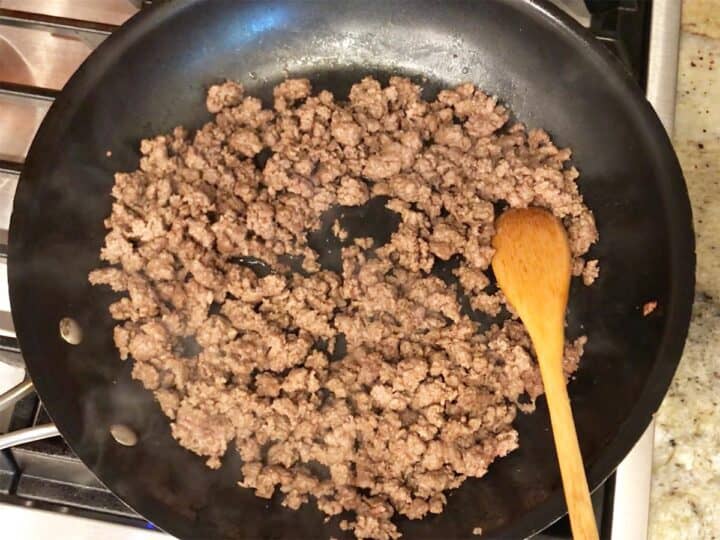 Cooking the ground beef in a skillet.