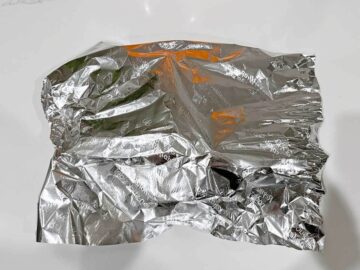 The patties are resting, covered in foil.