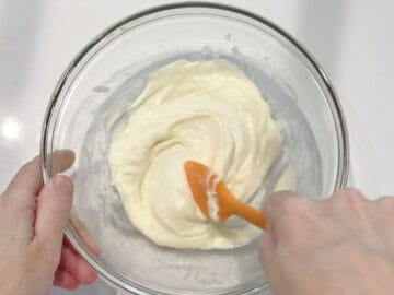 Mixing the melted cheeses in a bowl.