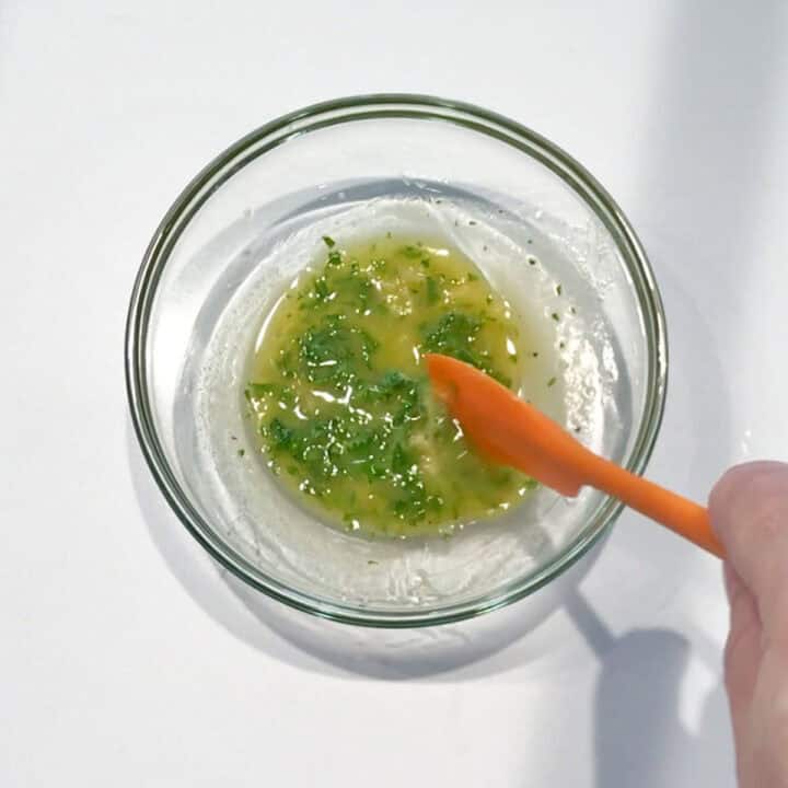 Mixing melted butter with garlic and parsley.