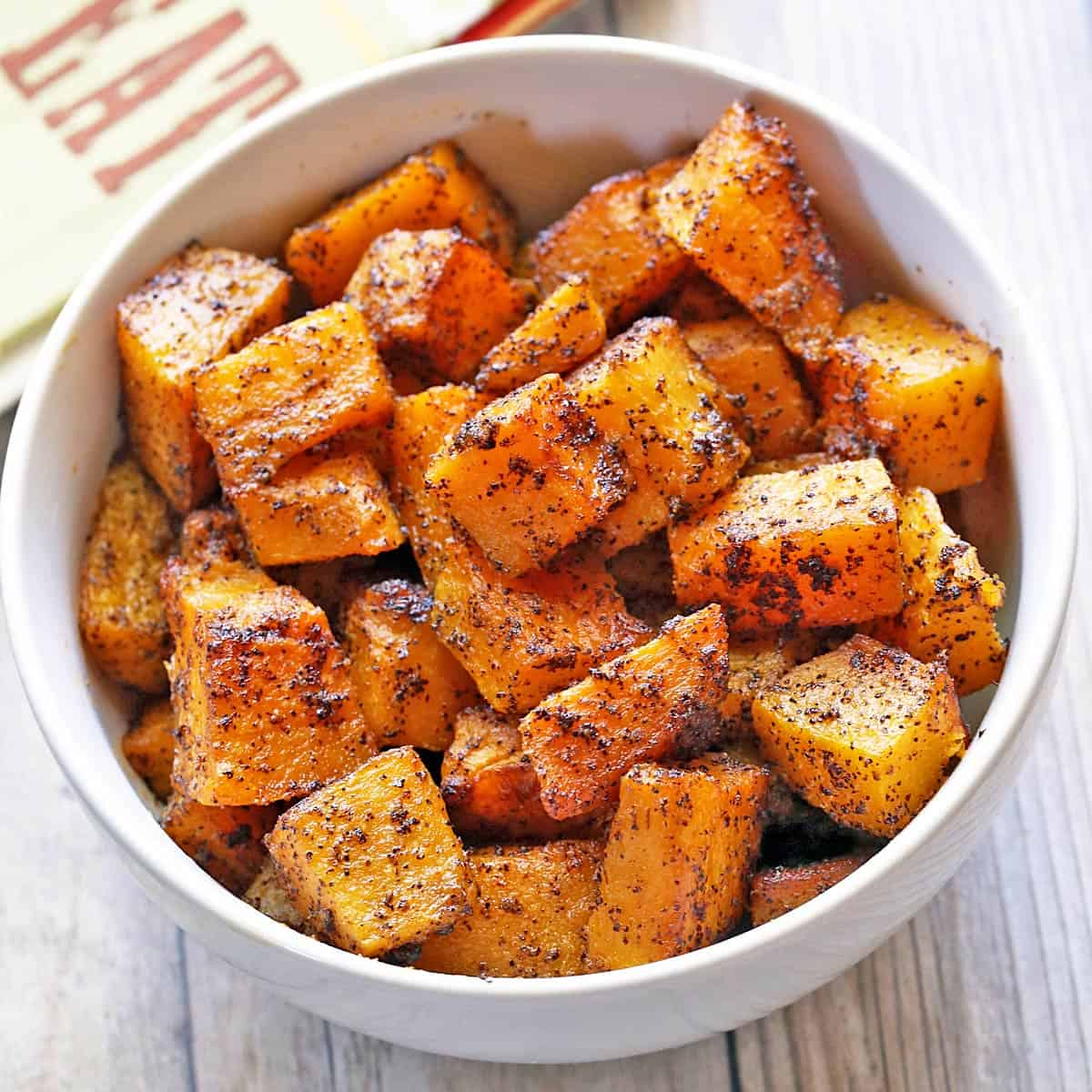 Roasted butternut squash is served in a white bowl.