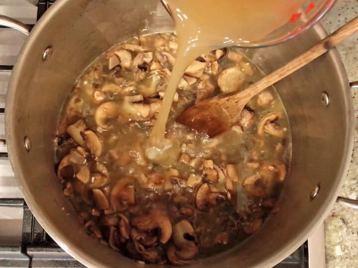 Adding broth to the stockpot.