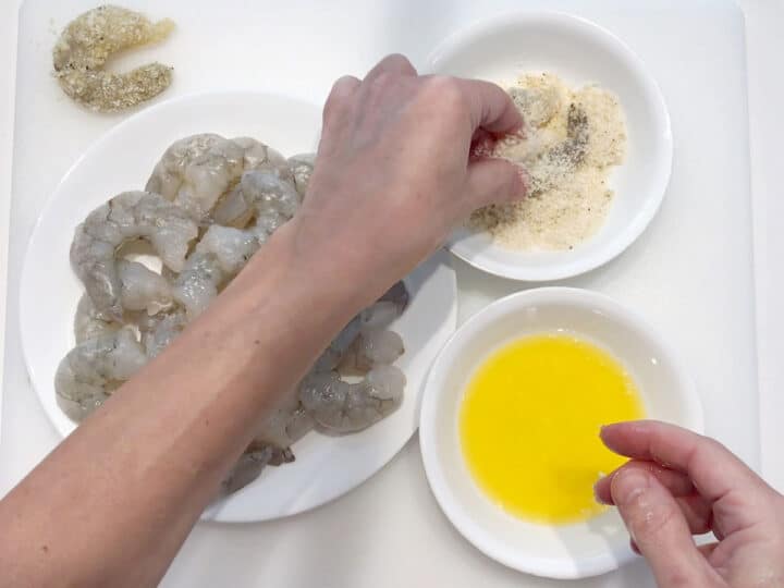 Dredging a shrimp in the parmesan mixture.