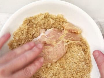 Dredging the chicken tenders in crushed pork rinds.