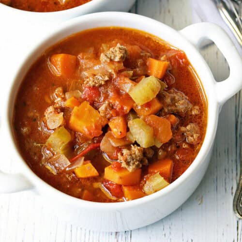 Vegetable beef soup is served in a white bowl.