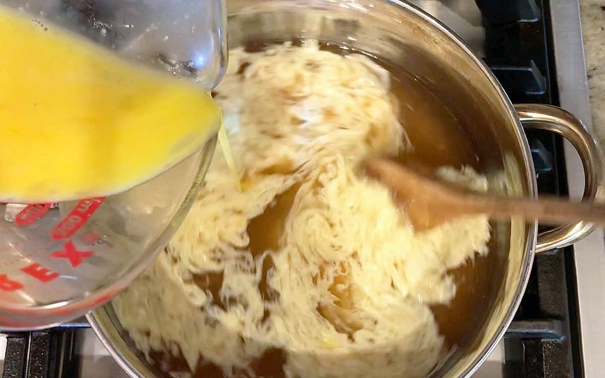 Pouring the eggs into the hot broth.