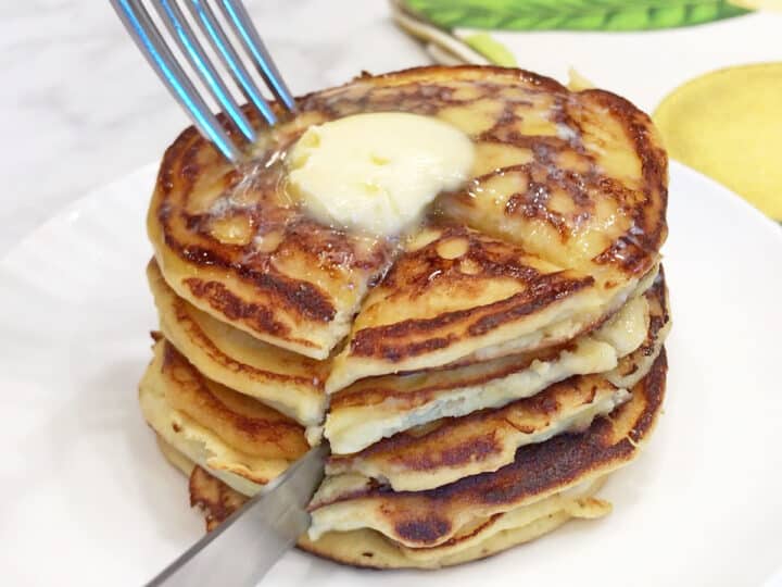 Cutting a stack of pancakes with a knife and fork.