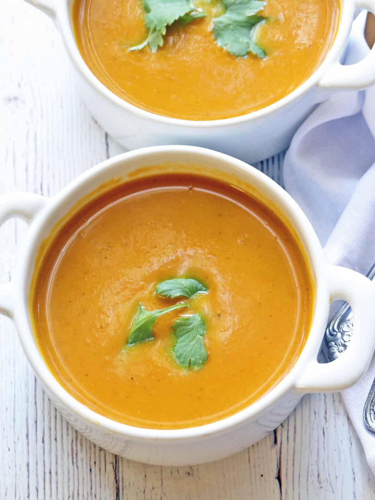 Pumpkin curry soup is served in white bowls.