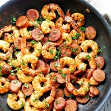 Shrimp and sausage are served in a skillet.