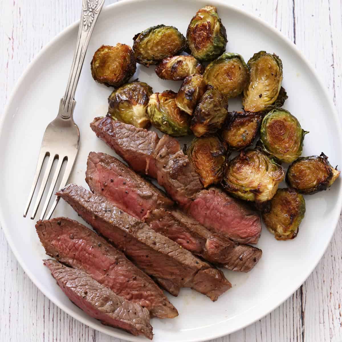 Top sirloin steak is served with Brussels sprouts.