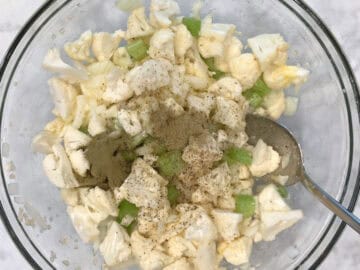 Veggies, melted butter, and spices in a bowl.