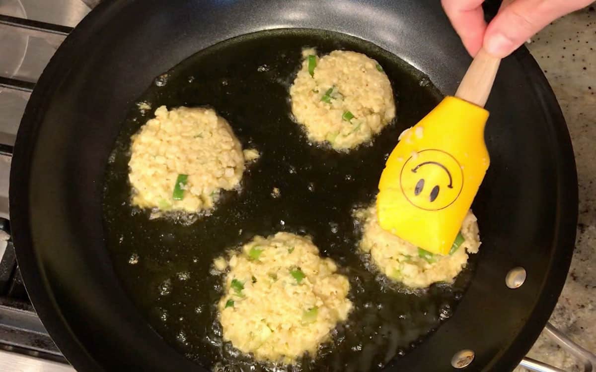 Adding the fritters toi the skillet.