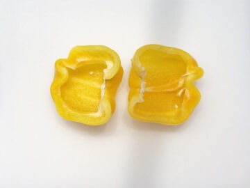 A halved yellow bell pepper on a cutting board.
