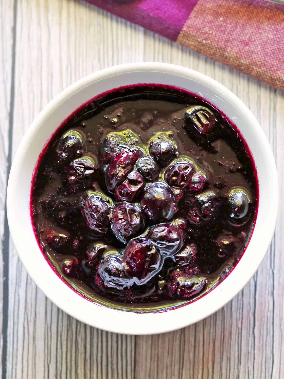 Blueberry compote is served in a white bowl with a napkin.