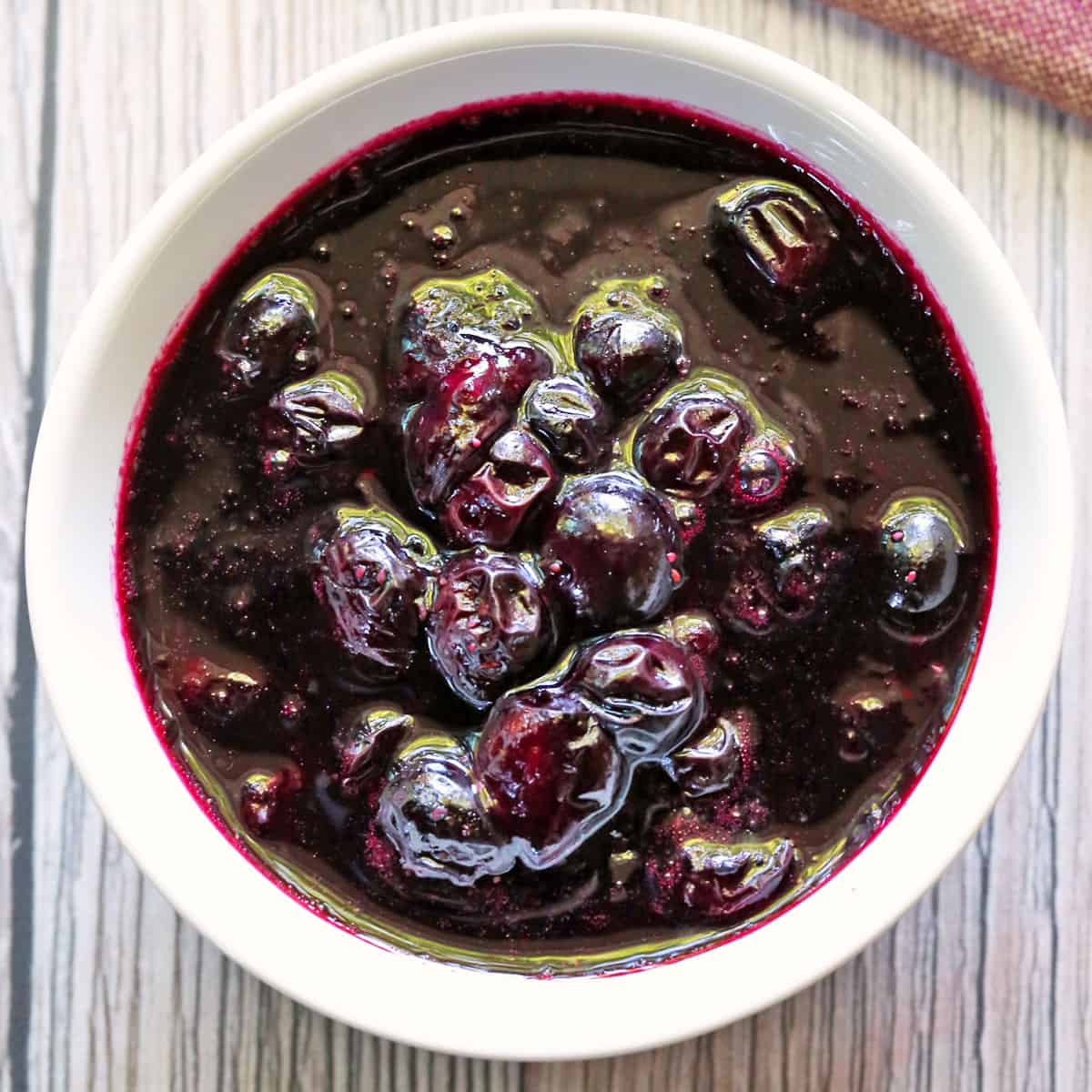 Blueberry compote is served in a white bowl.