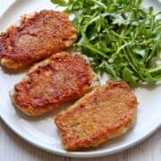 Keto fried pork chops are served on a white plate.