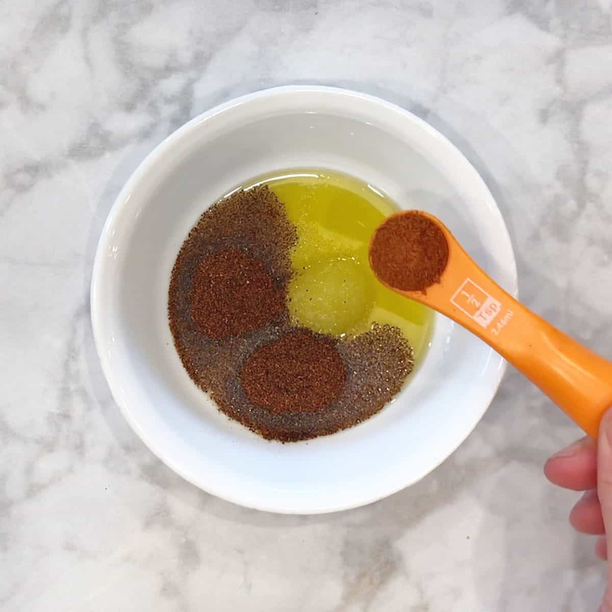 Adding the rub ingredients to a bowl.