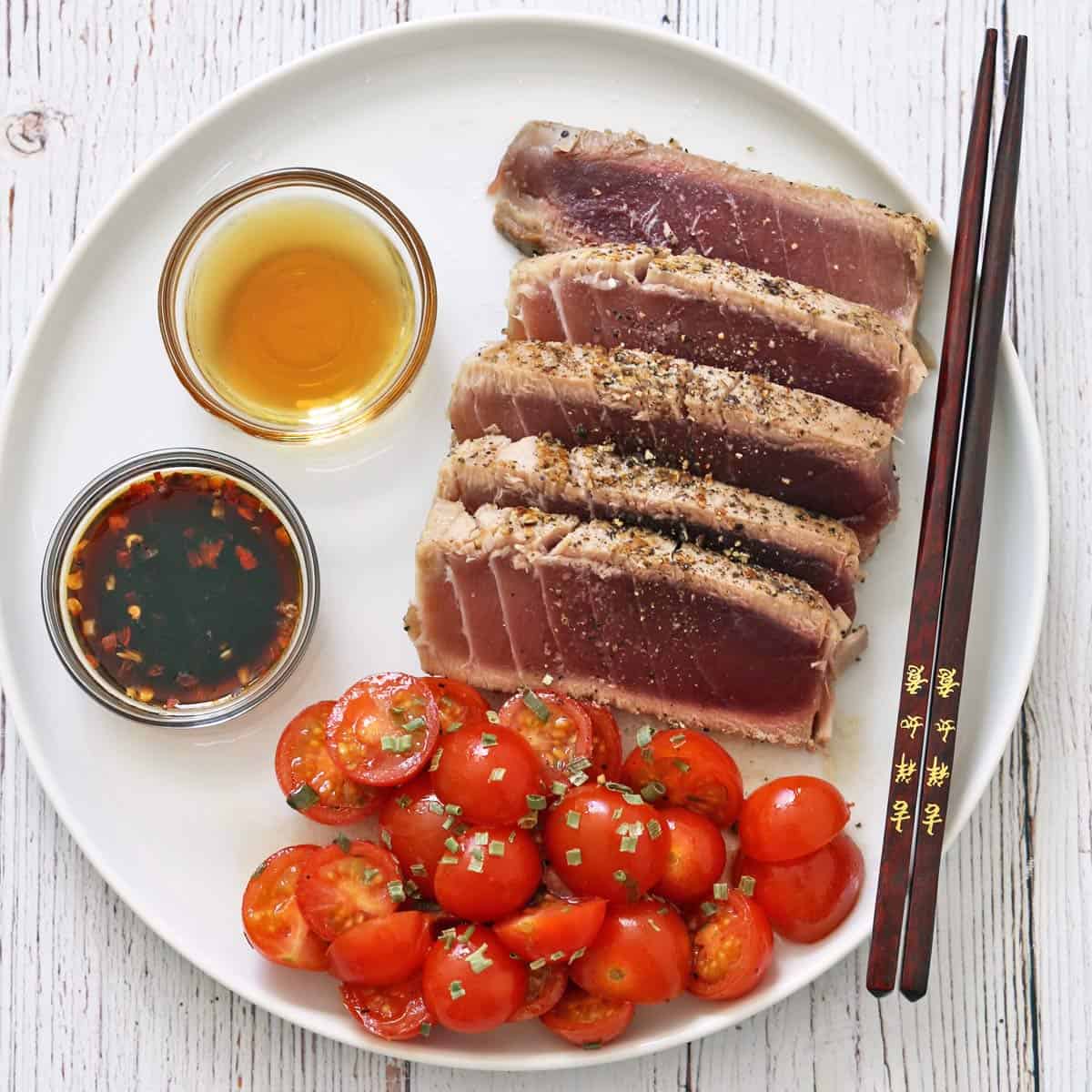 Seared tuna steak is served with tomato salad.