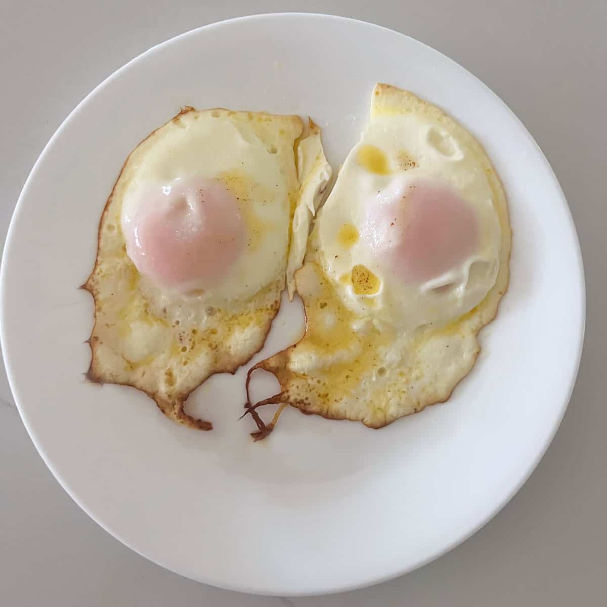 Two sunny side up eggs with white film on their yolks.