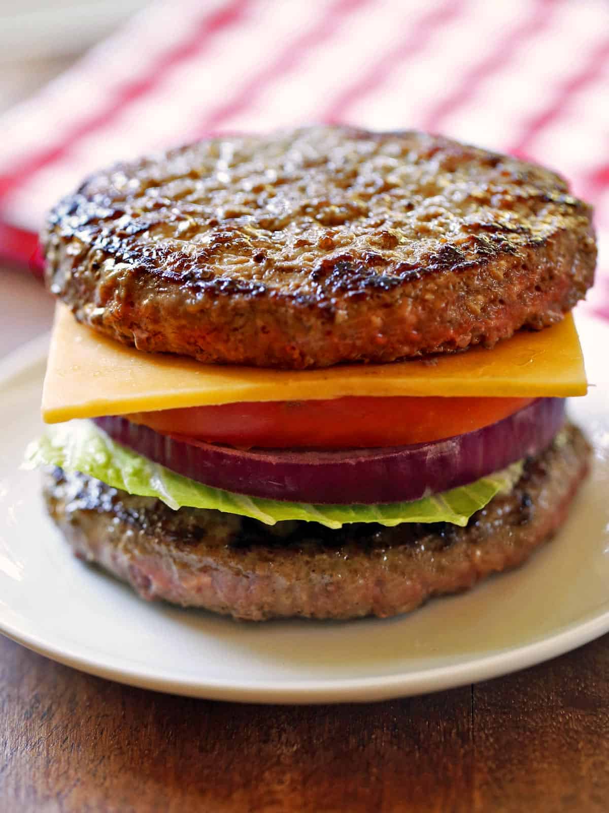 A bunless burger is served on a white plate.