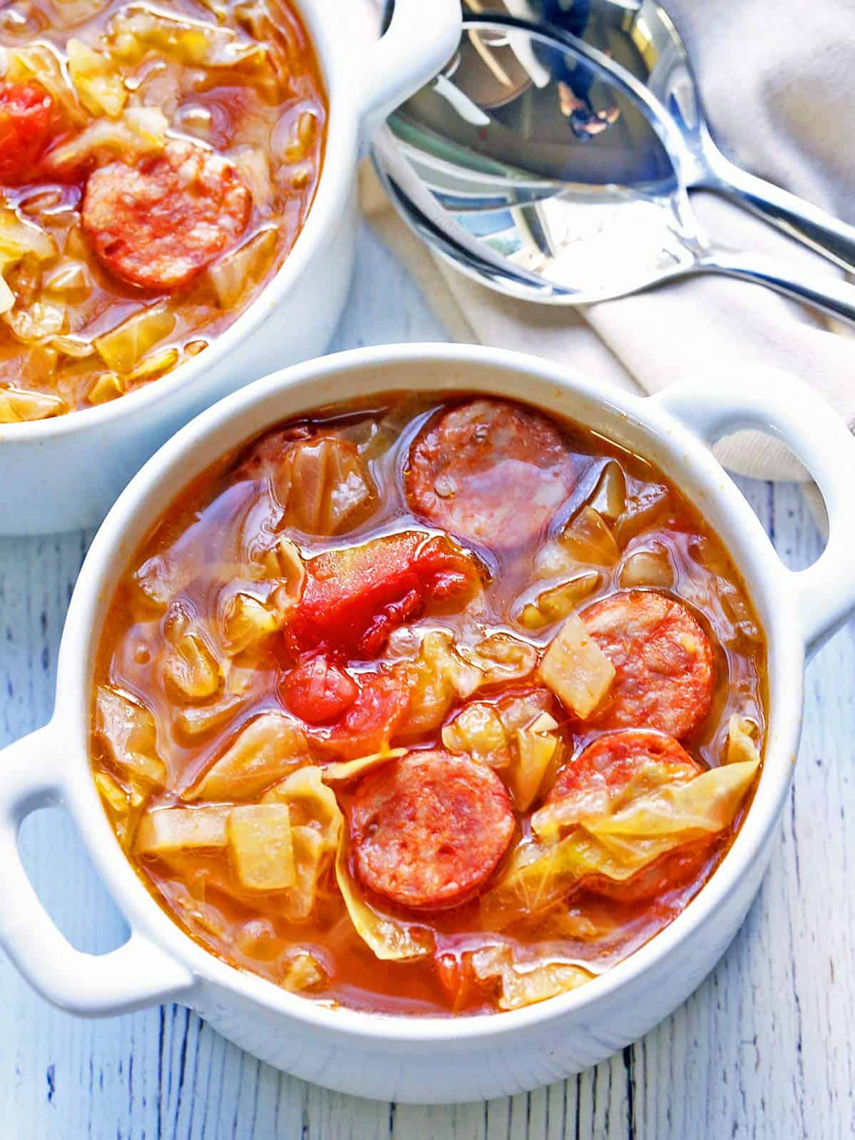 Cabbage soup is served in white bowls.