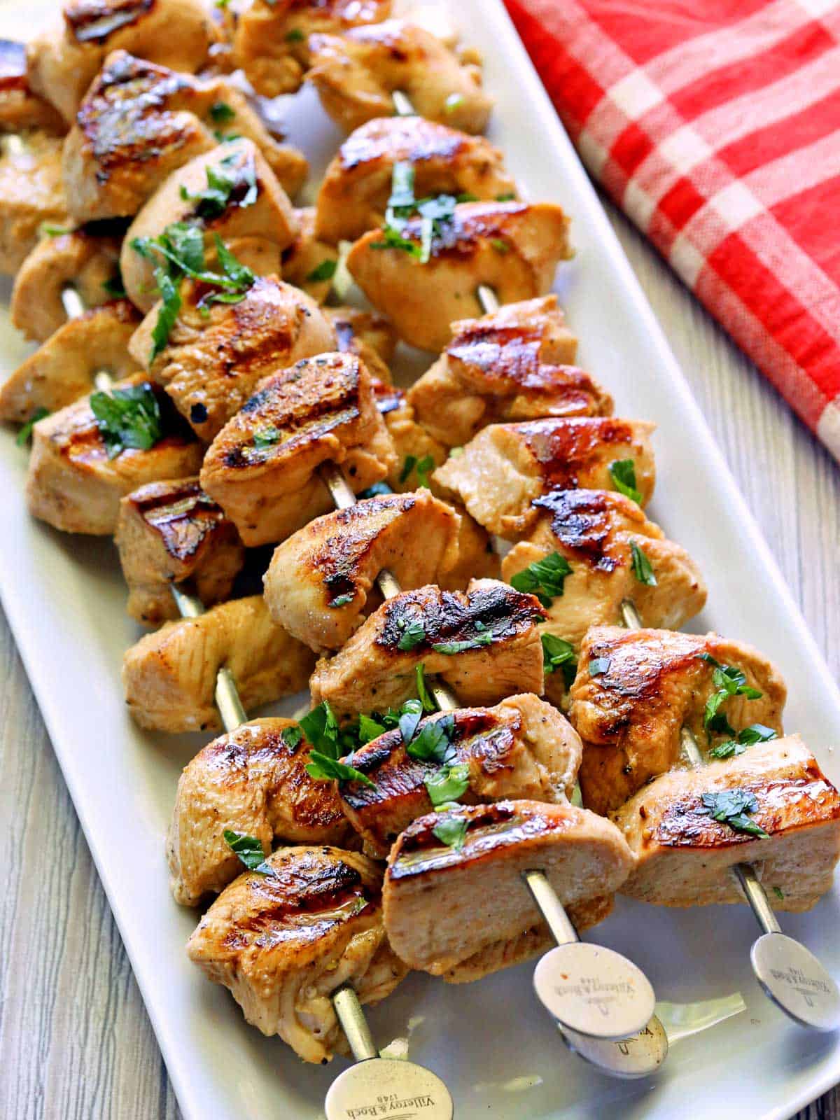 Grilled chicken skewers are topped with chopped parsley.