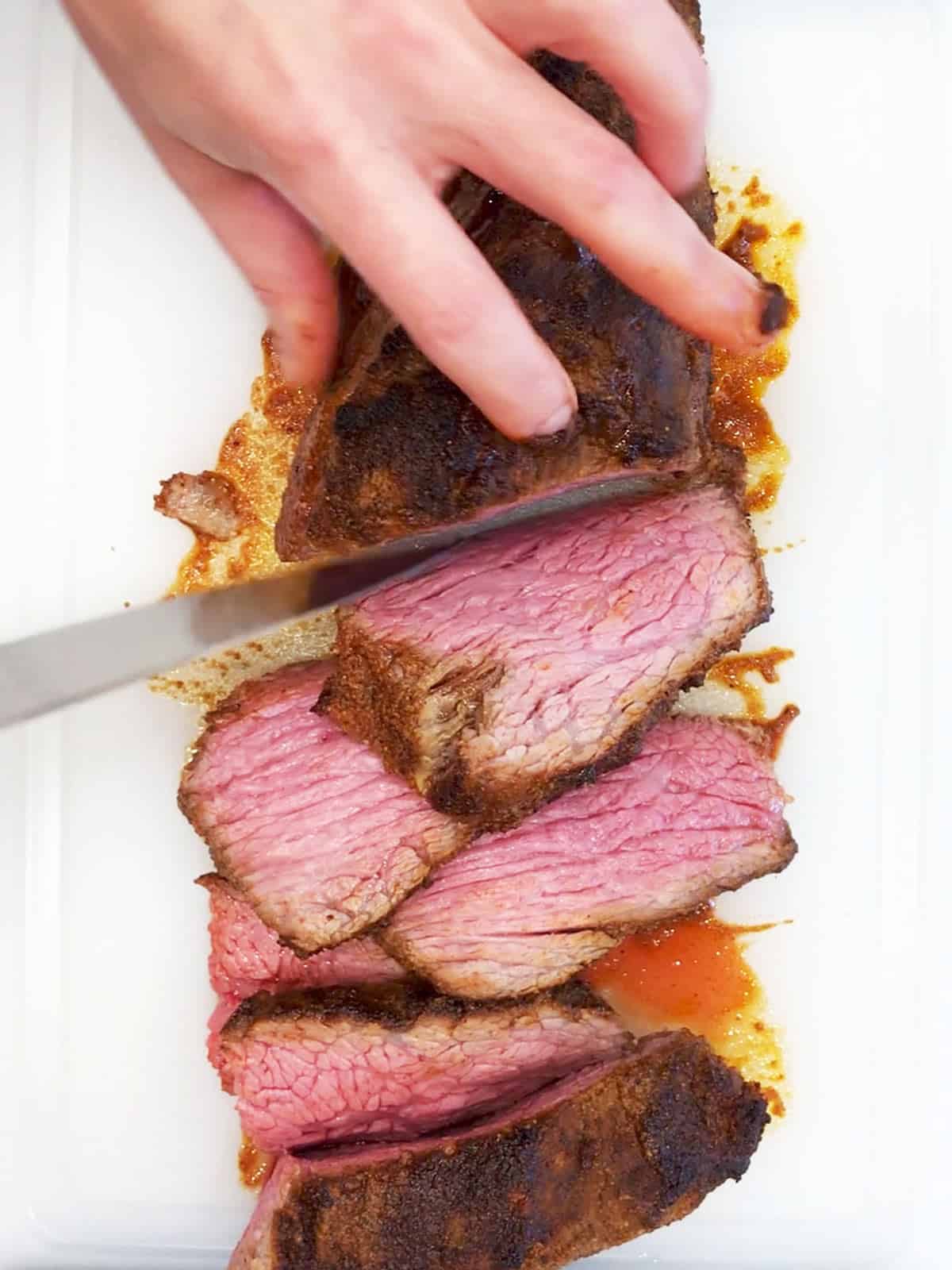 A roasted tri-tip is sliced on a cutting board.