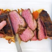 Slicing a roasted tri-tip on a cutting board.