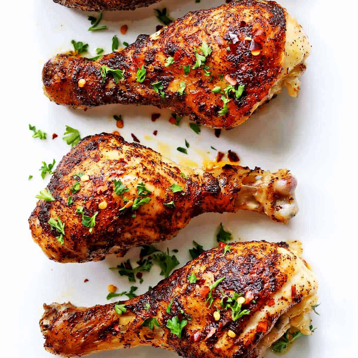 Spicy drumsticks are served on a white plate.