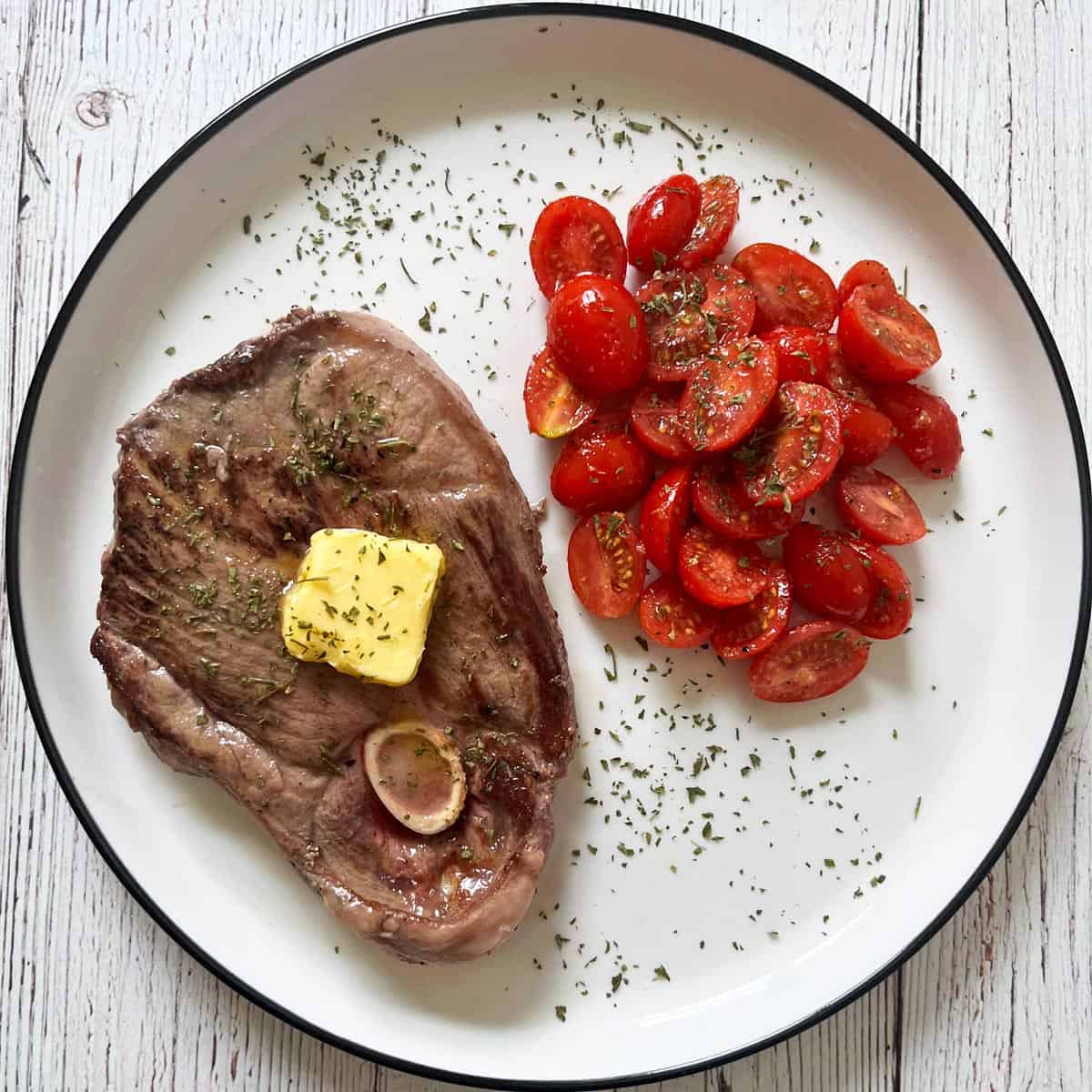 A lamb steak is served with tomato salad.