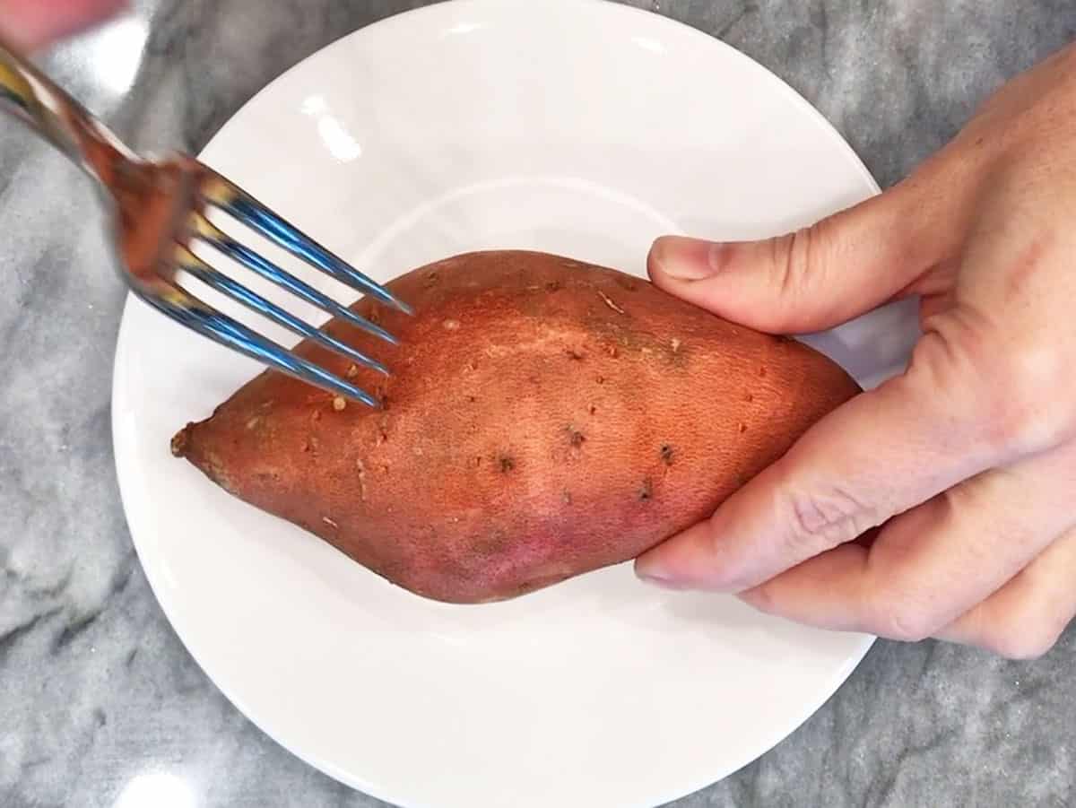 Piercing the potato with a fork.